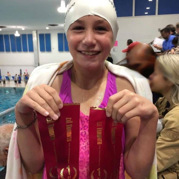 Cochlear implant recipient holds up swimming ribbons