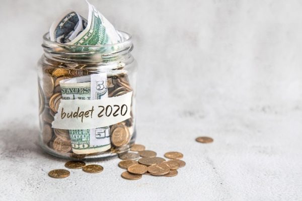 A mason jar of change and cash sit with a label saying budget 2020