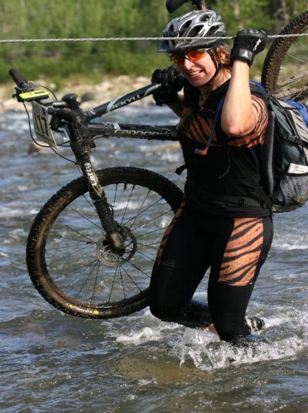 Caroline proudly carries her bike across a river