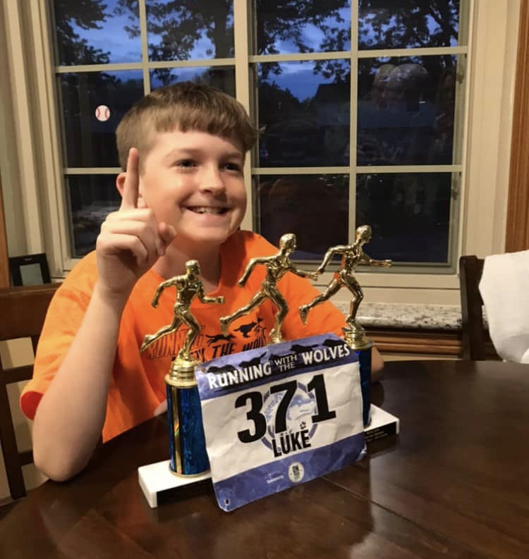 Child with congenital hearing loss posing in front of trophies