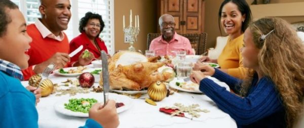 A family sits around the Thanksgiving dinner table. They are working on listening in noisy environments. 