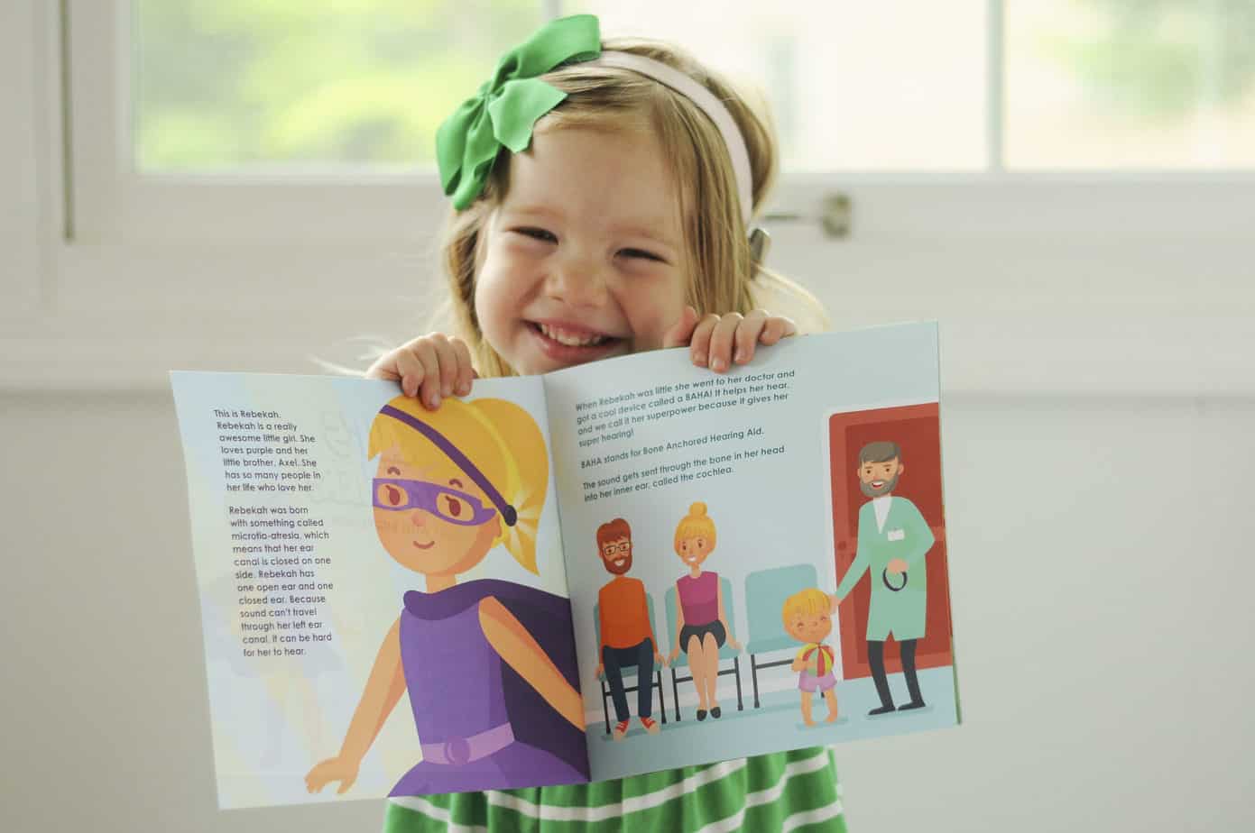 Rebekah, a child born with microtia and atresia, with her book
