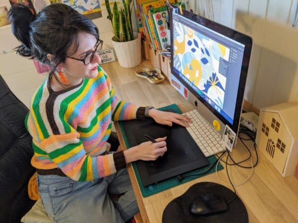 Artist, Sophie, sits at her desk working on art that inspired cochlear illustrations