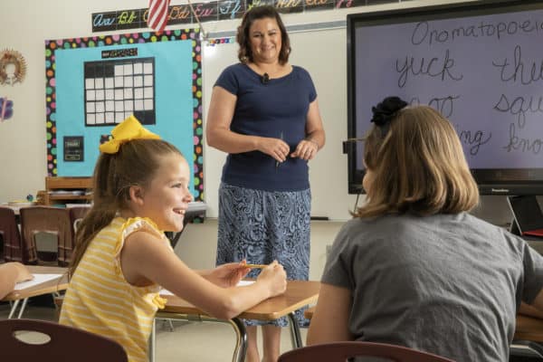 A teacher stands in front of a class as she will help students with hearing loss.